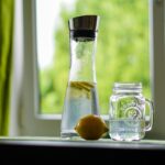 Donna che beve un bicchiere d'acqua, simbolo di idratazione e metabolismo attivo.