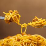 Un piatto di pasta fumante con sugo, simbolo di una dieta quotidiana.
