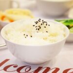 Uomo che misura la glicemia con un glucometro accanto a un piatto di riso bianco.